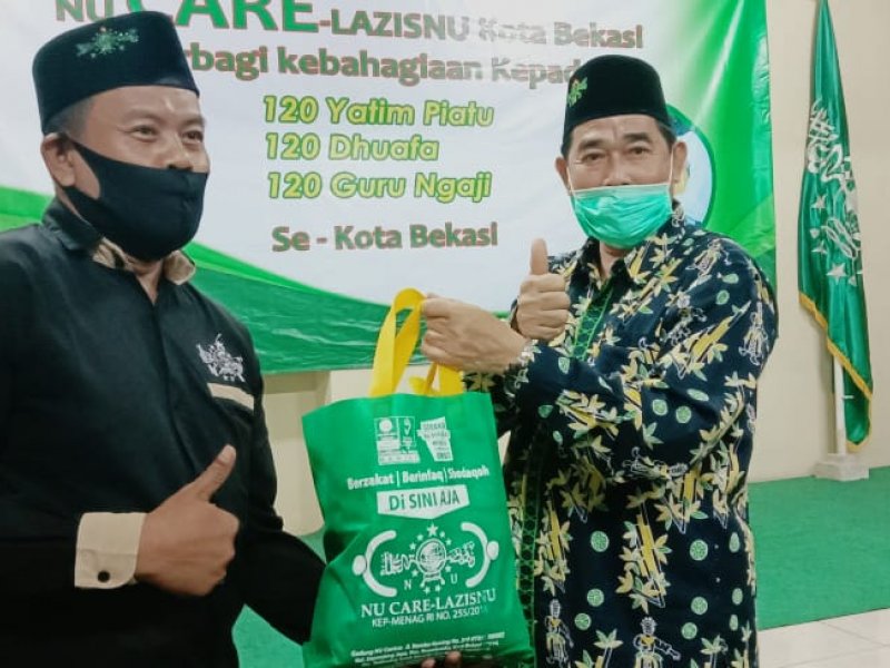 Ketua PCNU Kota Bekasi H. Madinah (kanan) menyerahkan simbolis paket kepada MWC Mustika Jaya