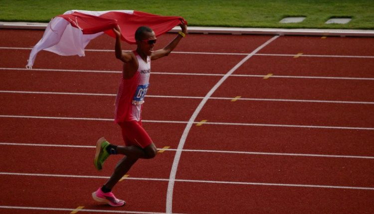 Agus Prayogo mengibarkan bendera Merah Putih jelang garis finis marathon SEA Games 2019. ANTARA