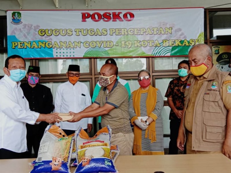 Ketua FKUB Kota Bekasi Abdul Manan (kiri) menyerahkan simbolis bantuan kepada Kepala BPBD Agus Harpa