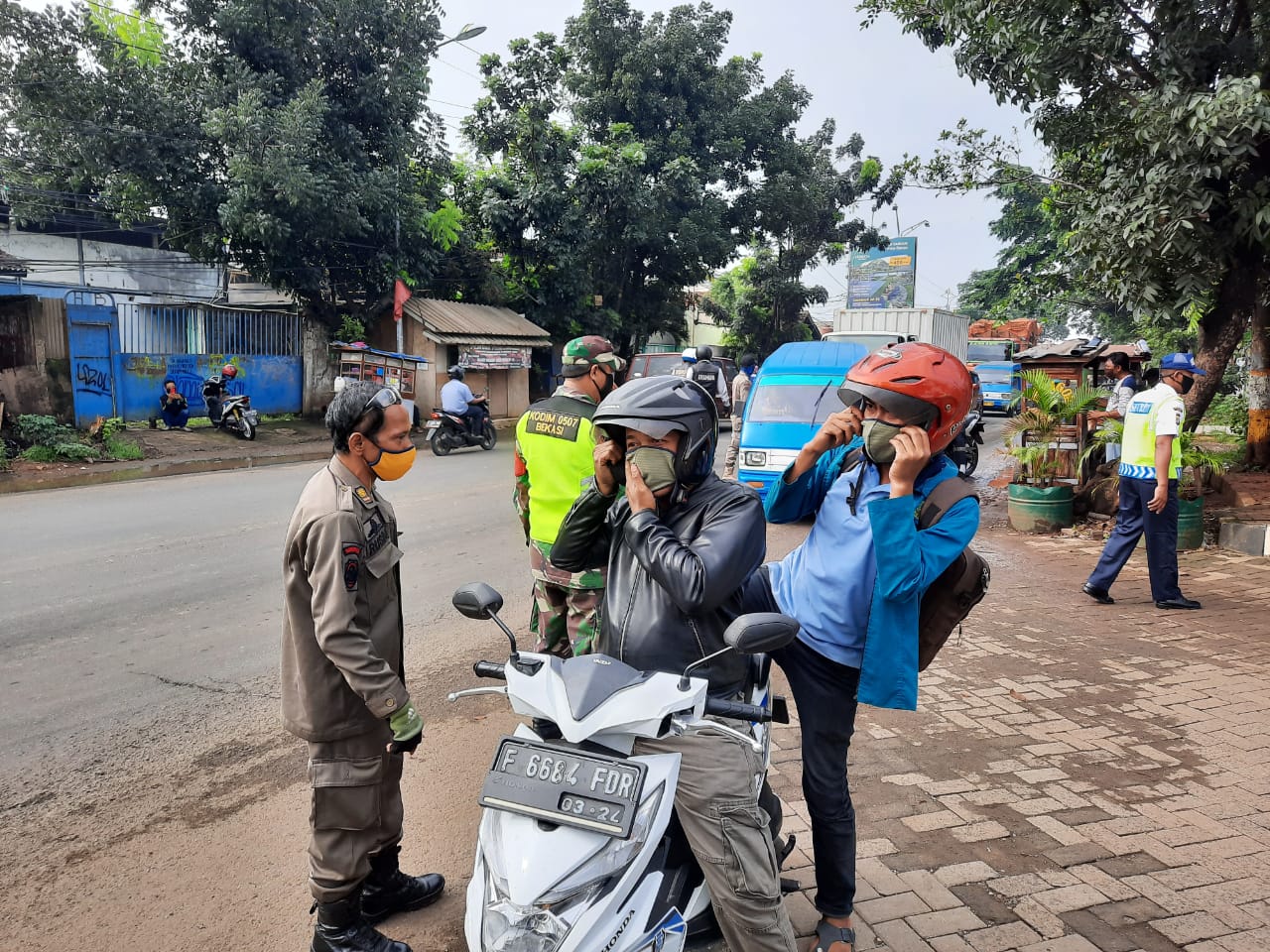 Petugas Satpol PP Kota Bekasi menghentikan pengendara motor yang berboncengan saat PSBB