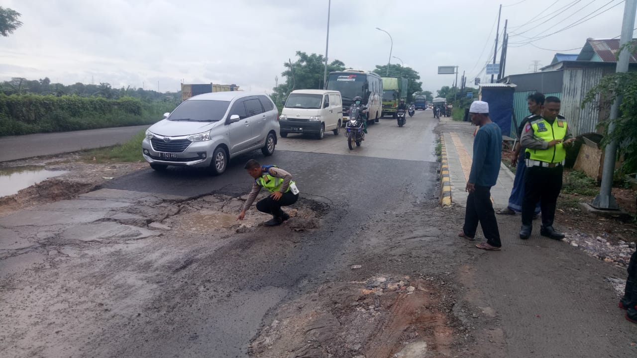 Satlantas Polres Metro Bekasi menambal jalan yang rusak akibat curah hujan yang tinggi