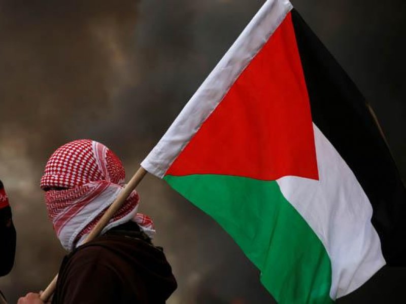 Seorang warga memegang bendera Palestina (dok/REUTERS)